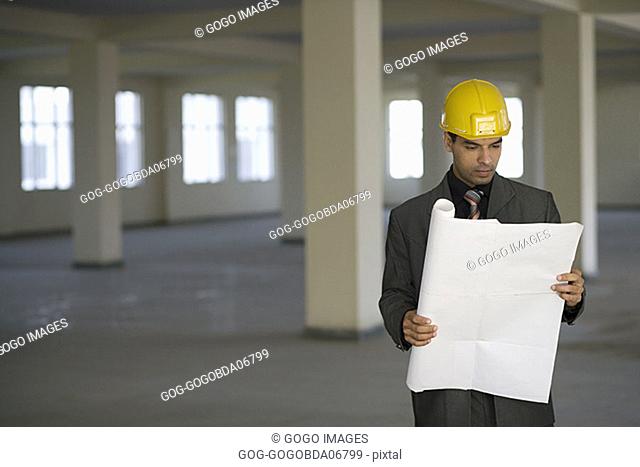 Businessman in hardhat reading blueprints