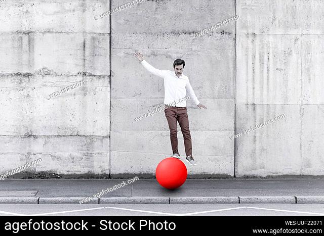 Man balancing on fitness ball against wall