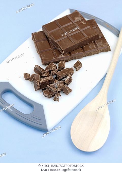 Cooking chocolate chopped on a cutting board isolated against a blue background