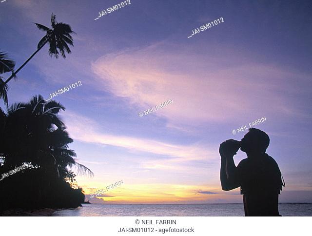 Man blowing inro a seashell, Samoa