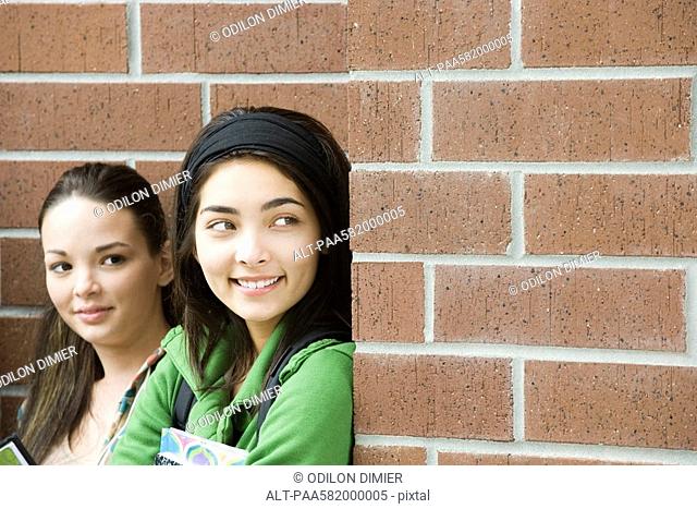 Teenage girl with friend, peeking around corner