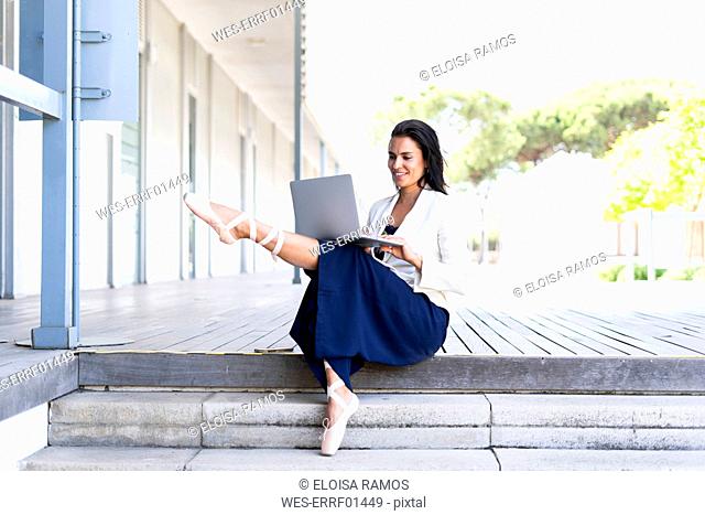 Female ballet dancer using laptop sitting on steps