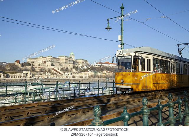 Traditional yellow tram in Budapest, Hungary. Buda Castle in the Distance