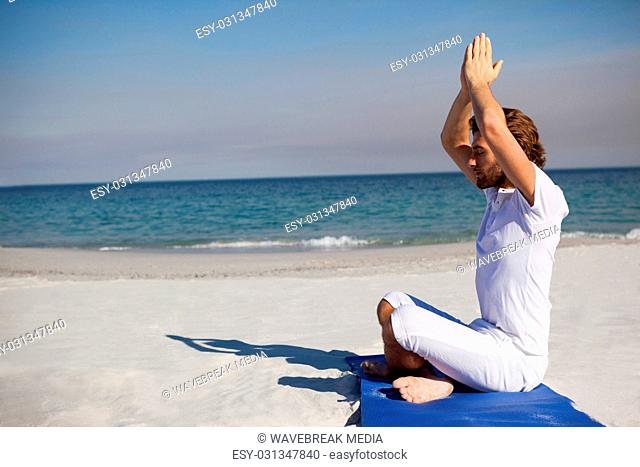 Side view of man meditating at beach