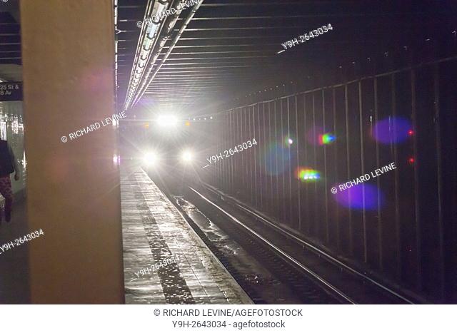 The bright lights of a NYCTA subway track inspection train are seen as the train passes through the West 23rd Street station