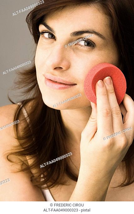 Young woman using cosmetic sponge
