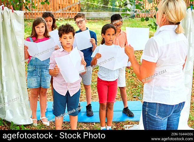 Kinder mit Notenblätter singen zusammen im Chor im Ferienlager oder Sommercamp