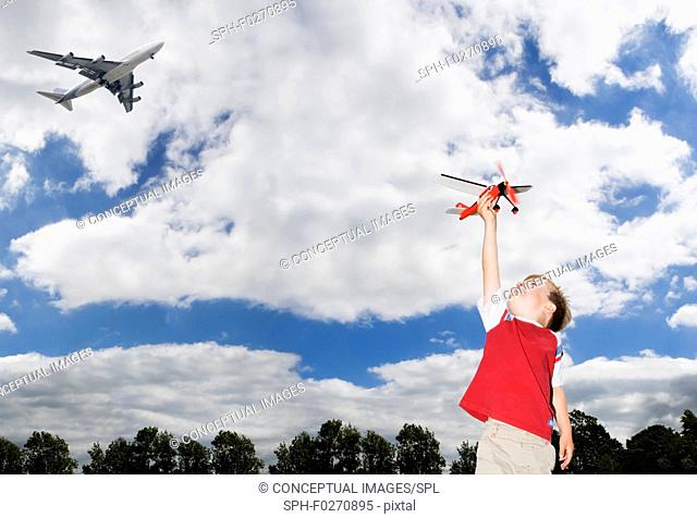 Boy playing with toy plane with plane flying overhead