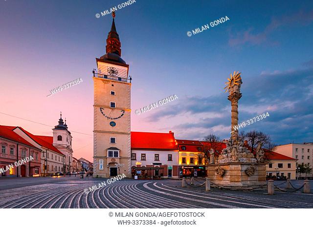 Trnava, Slovakia - April 9, 2019: City tower and Holy Trinity Statue in the main square of Trnava, Slovakia