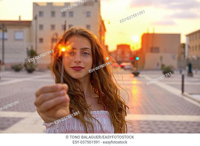 Teen girl with sparklers at sunset sky in the city