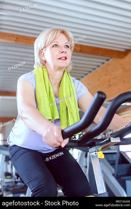 Senior woman training on an exercise bike in the gym