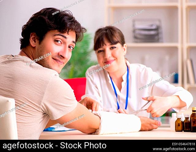 Young man with bandaged arm visiting female doctor traumatologist