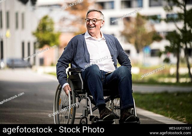 Happy senior man sitting on wheelchair in the city