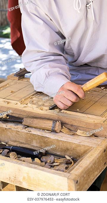 craftsman carving wood in a medieval fair, carpentry tools