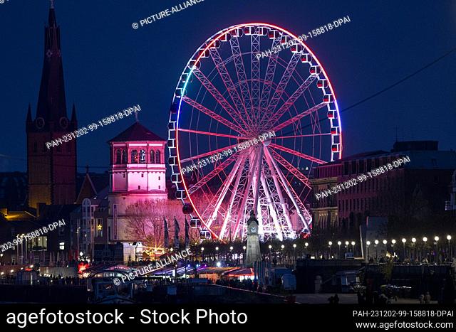 02 December 2023, North Rhine-Westphalia, Duesseldorf: View of the Rhine promenade with illuminated Ferris wheel ""Wheel of Vision""