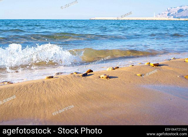 Beautiful view of wet sand, beach seashore coastline, foamy sea waves, stones on sunny windy day. Summer, holiday, vacation, travelling, tourism, seascape ocean