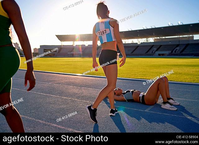 Tired female track and field athlete laying on track after competition