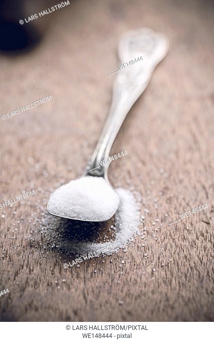 Salt on a spoon in close up. Wooden table as background with copy space