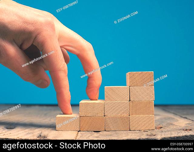 Hand of a businessman taking the next step on wooden stairs, motivation or career concept
