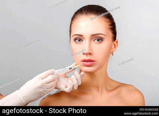 Portrait of young beautiful woman getting cosmetic lifting injection in lips. Plastic Surgery. Cosmetic Treatment