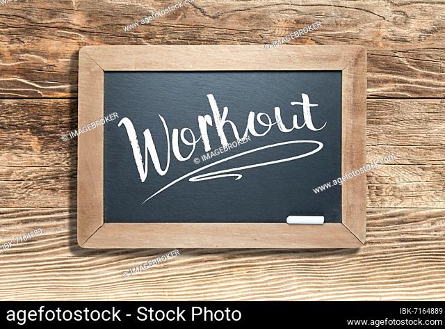 Workout written on slate chalk board against aged wood background