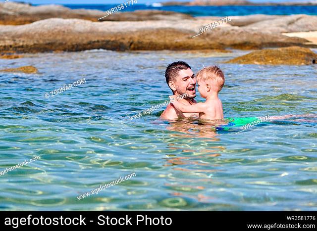 Two year old toddler boy on beach with father