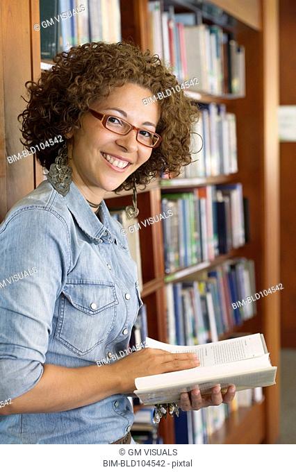 Hispanic woman reading book in library