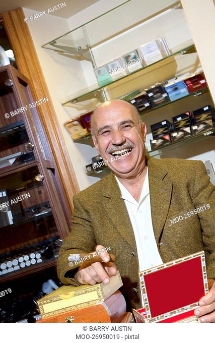 Portrait of cheerful mature man smoking cigar in tobacco store