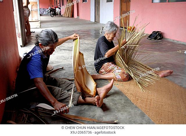 Malaysia, Sarawak, bidahyu women sitting inside long house weaving a bamboo basket