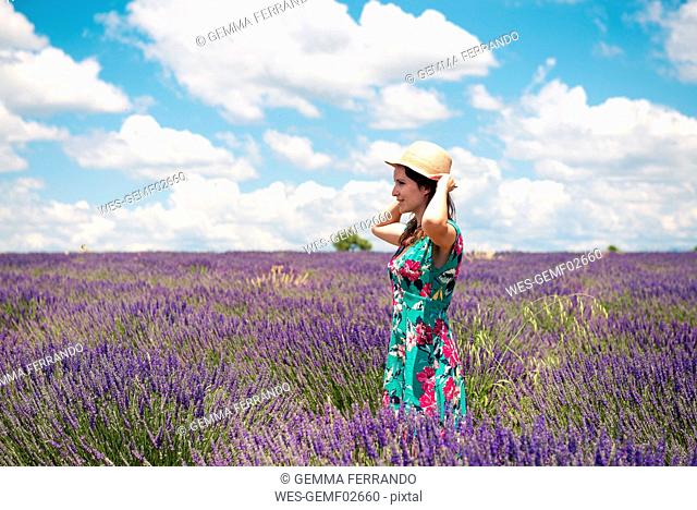 France, Provence, Valensole plateau, woman with straw hat standing in lavender field in summer