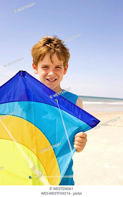 Germany, Baltic sea, Boy 8-9 holding kite, portrait, close-up
