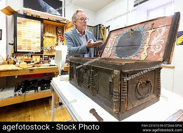15 October 2023, Thuringia, Erfurt: Ronald Krüger, restorer of wooden cultural property, shows a wooden chest from the dyers' guild dating from 1694 that is...