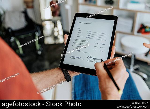 Male patient digitally signing form in practice