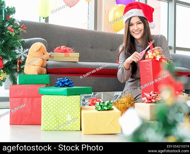Beautiful Asian women smile happily. She is wrapping up gifts at her house to have fun. She hires to make gifts for clients during the New Year's holiday season