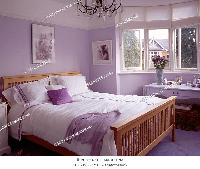 White bedlinen on wooden bed in mauve bedroom