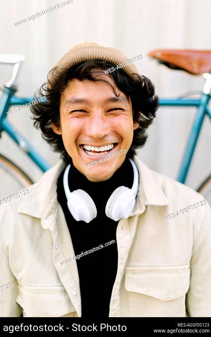 Cheerful man squinting eyes in front of bicycle