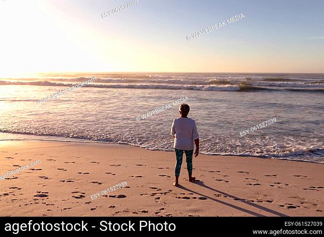 Rear view of senior african american woman walking on the beach