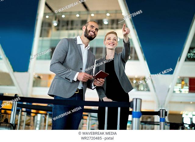 Businesswoman standing with her colleague and pointing at the distance