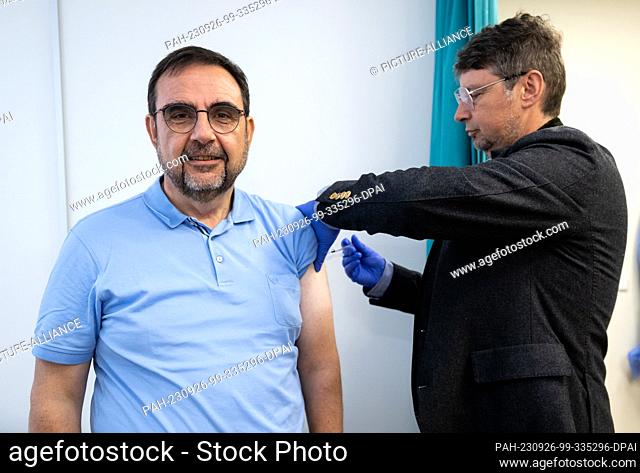 26 September 2023, Bavaria, Munich: Klaus Holetschek (l, CSU), Bavarian Minister of Health, gets a flu vaccination from Wolfgang Ritter