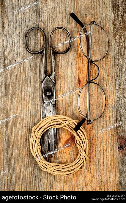 old scissors, glasses and hank of packthread over wooden background