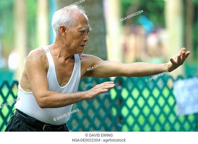 An Elderly Man Practices Tai Chi in a Park in Hong Kong
