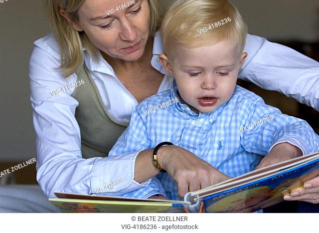 Muter child reads from a picture book before - , , Germany, 09/10/2006