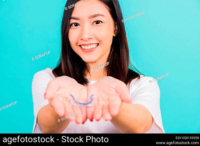 Portrait young Asian beautiful woman smiling holding silicone orthodontic retainers for teeth on hand palm, Teeth retaining tools after removable braces