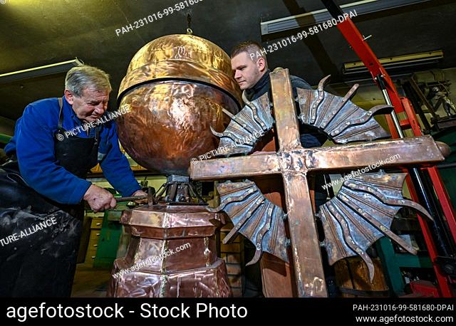 16 October 2023, Brandenburg, Angermünde: Master metalworker Wilfried Schwuchow (l) works in his workshop together with son Paul on the crowning of the...