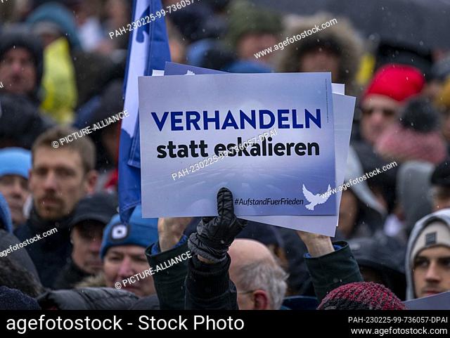 25 February 2023, Berlin: A participant of the demonstration holds up a sign with the inscription ""Negotiate instead of escalate""