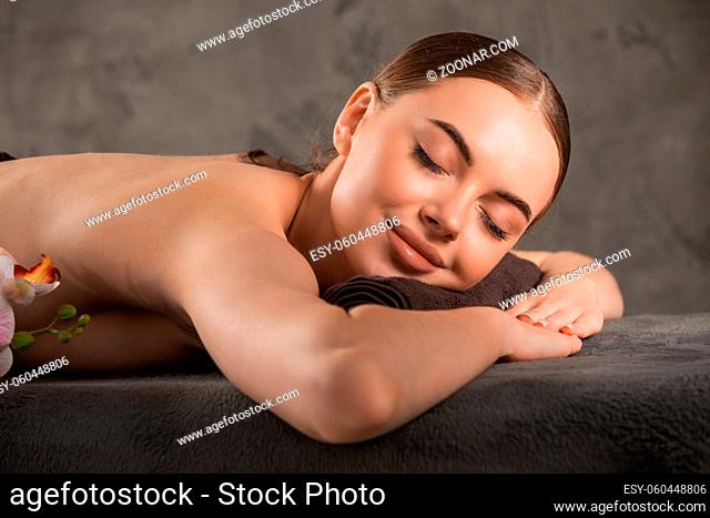 Close up of a smiling woman relaxing on a lounger with eyes closed in a wellness center