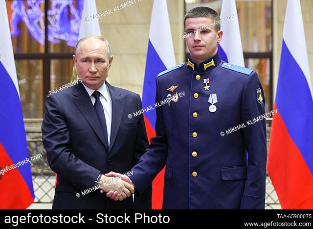 RUSSIA, MOSCOW - DECEMBER 19, 2023: Russia's President Vladimir Putin (L) and Hero of Russia, Private Yevgeny Kudinov shake hands during a ceremony to present...