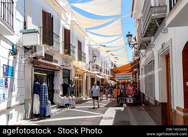 Nerja, Spain - May 28, 2019: People walking in a charming narrow shopping street in the city centre