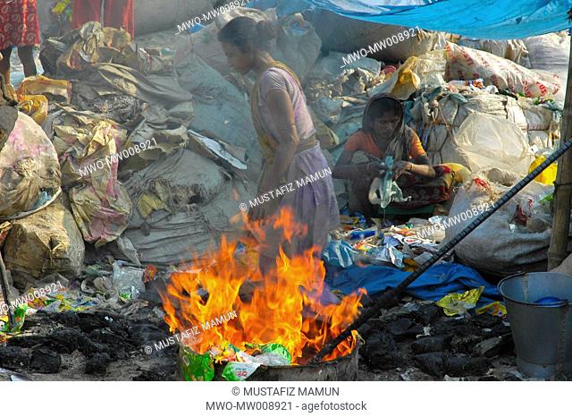 Bangladeshi women burn waste plastic on the bank of Buriganga River near Kamrangir Char February 11, 2007