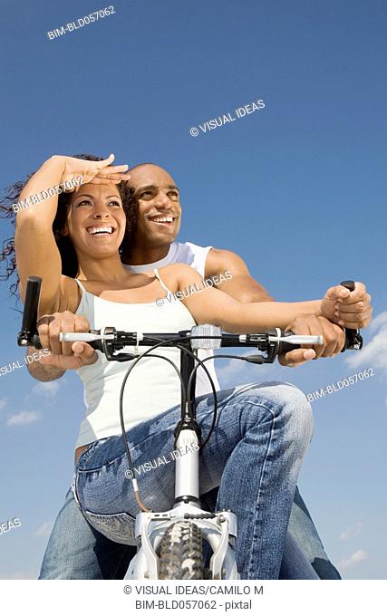 Multi-ethnic couple sitting on bicycle